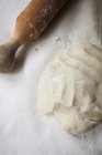 Closeup top view of yeast dough and a rolling pin — Stock Photo