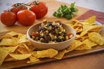 Corn salsa with black beans and tortilla crisps on wooden desk — Stock Photo