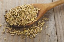 Dried fennel seeds on a wooden spoon over wooden surface — Stock Photo