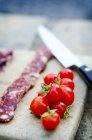Tranches de chorizo sur une planche de bois avec tomates cerises — Photo de stock
