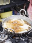 Casava frita en aceite caliente en un mercado callejero local - foto de stock