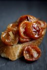 Bruschetta topped with cherry tomatoes over black wooden surface — Stock Photo