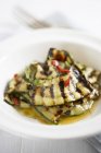 Zucchine grigliate marinate con menta, olio d'oliva e peperoncino su piatto bianco — Foto stock