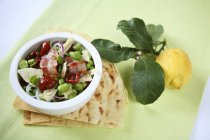 Insalata di fave - бобовий салат із сушеними помідорами та беконом у білій страві — стокове фото