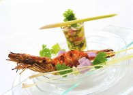 Gamberi grigliati con un tuffo vegetale su un piatto di vetro su sfondo bianco — Foto stock