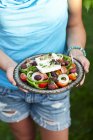 Woman holding plate of Greek salad — Stock Photo