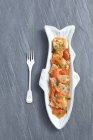 Pollack con peperoni, aglio e pomodori su piatto su superficie di legno con forchetta — Foto stock