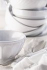 Крупный план белых керамических чаш с ложкой на ткани — стоковое фото