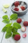 Lychees with mint and lime wedges — Stock Photo