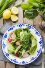 A plate of fresh salad ingredients on plate over wooden surface — Stock Photo