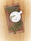 Top view of a mortar with fresh herbs on a wooden board — Stock Photo