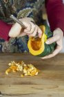 Woman hollowing out acorn squash — Stock Photo