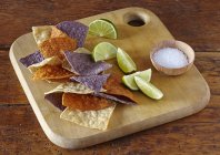 Chips de tortilla coloridos com limas e sal — Fotografia de Stock