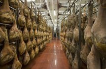 Rows of hanging hams in a drying room — Stock Photo