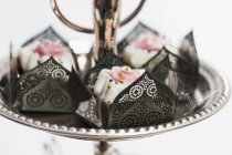 Vista de primer plano de la confitería de chocolate en elegantes cajas de papel decoradas con rosas y perlas de azúcar dorada - foto de stock