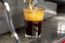 Espresso verter de la máquina en vidrio - foto de stock