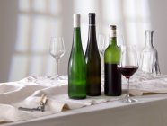 Copa de vino tinto con botellas - foto de stock