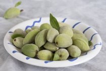 Plate of green fresh almonds — Stock Photo