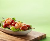 Garnelenspieße mit Tomaten auf Salatbeet auf Holztisch — Stockfoto