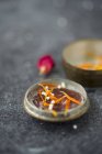 Globules in the lid of an old tin with dried marigold petals and a dried rose petal — Stock Photo