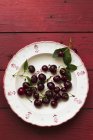 Cherries on floral-patterned plate — Stock Photo