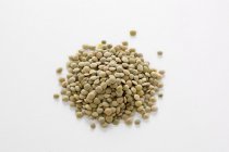Closeup view of green lentils in heap on white surface — Stock Photo