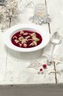 Beetroot soup with pierogi on white plate over wooden surface — Stock Photo