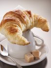 Croissant em cima de uma xícara de café — Fotografia de Stock