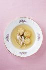 Brühe mit Frikadellen und Hühnerstreifen auf weißem Teller über rosa Oberfläche — Stockfoto