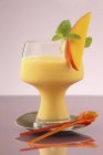 A mango and carrot lassi with lemon balm over small plate — Stock Photo