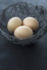 Raw Eggs in wire Easter nest — Stock Photo