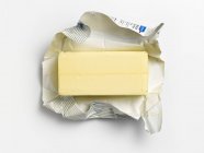 Top view of an unwrapped pat of butter on its wrapper — Stock Photo