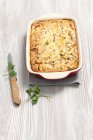 Mushroom and leek bake in dish over wooden table with knife — Stock Photo