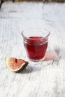 Verre de vin rouge avec une tranche de figue — Photo de stock