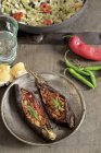Stuffed aubergines on black plate over wooden surface — Stock Photo