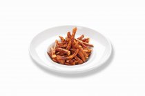 Bâtonnets de patates douces frites sur plaque blanche sur surface blanche — Photo de stock