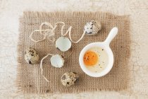 Top view of three whole quail eggs with a cracked open egg and shells — Stock Photo