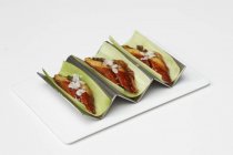 Unagi in cucumber leaves on white plate over white surface — Stock Photo