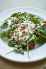 Salada de espinafre com molho de húmus, tomates e nozes em prato branco — Fotografia de Stock