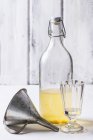 Bottiglia di liquore fatto in casa con bicchiere vintage e imbuto — Foto stock