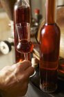 Vista ravvicinata del bicchiere di grappa di pino cembro vicino alle bottiglie — Foto stock