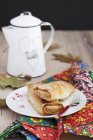 A mini apple and pumpkin strudel served with coffee  on plate over towel and jug — Stock Photo