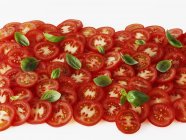 Tranches de tomates et feuilles de basilic — Photo de stock