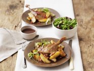 Entenconfit mit Bratkartoffeln und Salat — Stockfoto