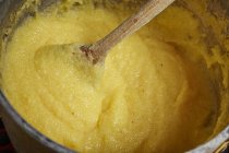 Cooked polenta in a pot with wooden spoon — Stock Photo