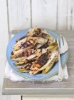 Grilled chicory with balsamic vinegar on blue plate over grey wooden surface — Stock Photo