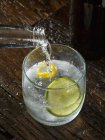 Nahaufnahme des Gießens von Tonic Water zu einem Glas Gin — Stockfoto