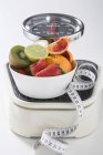 Closeup view of fresh fruit and tape measure on scales — Stock Photo