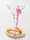 Nahaufnahme eines leeren Cocktailglases mit Flamingo-Stick auf Tanga-Sandale — Stockfoto
