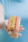 Femme tenant hot dog avec moutarde — Photo de stock